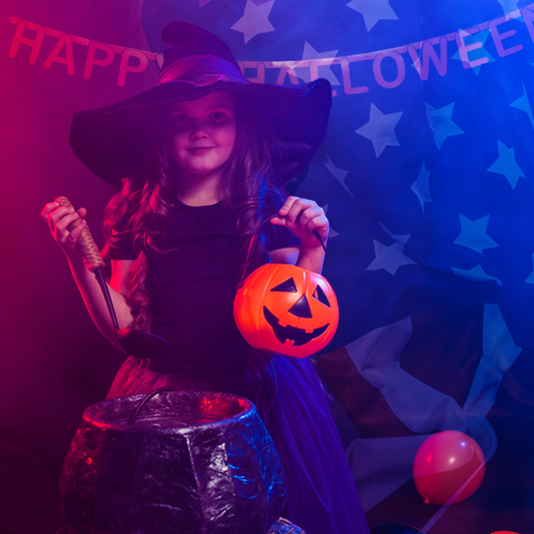 Girl dressed in Halloween costume standing in front of American flag.