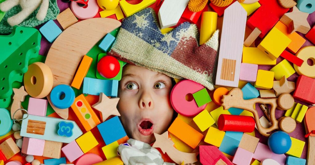 Child looking excited at pile of wooden toys made in USA.