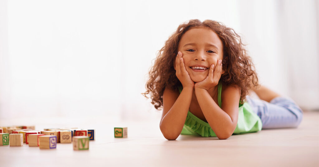 Smiling girl playing with alphabet blocks.