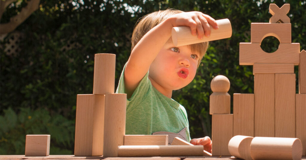 Young boy playing with wooden building blocks.
