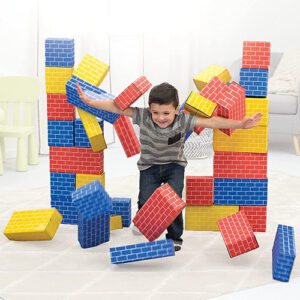 Happy boy bursting through wall of cardboard building blocks.