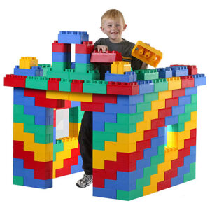 Boy building fort with big plastic building blocks.