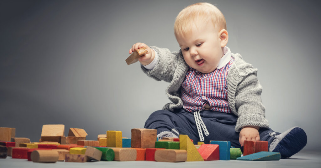 Cute baby playing with toy building blocks.