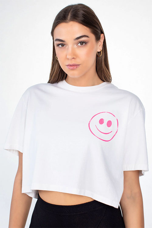 Young woman wearing white cropped t-shirt with pink smiley face print.
