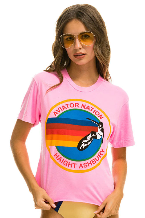 Woman wearing pink t-shirt with Aviator Nation logo.
