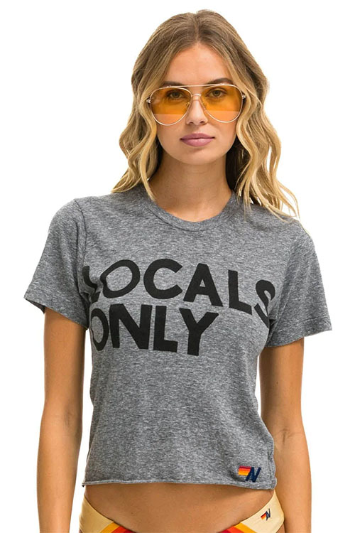 Woman wearing grey t-shirt with 'locals only' written across the chest.