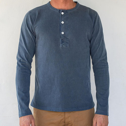 Man wearing blue crew neck t-shirt with long sleeves and buttons at the collar.