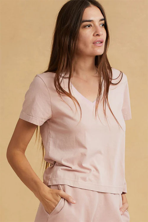 Woman wearing light pink, v-neck t-shirt.