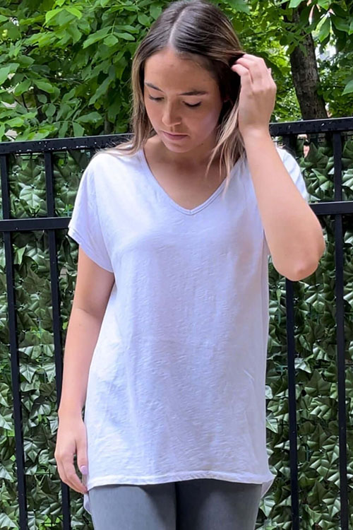 Woman wearing long white t-shirt with v-neck and short sleeves.