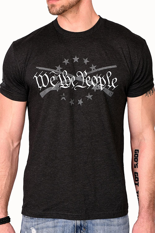 Man wearing black t-shirt with the words 'we the people' and 2 crossed muskets on the chest.