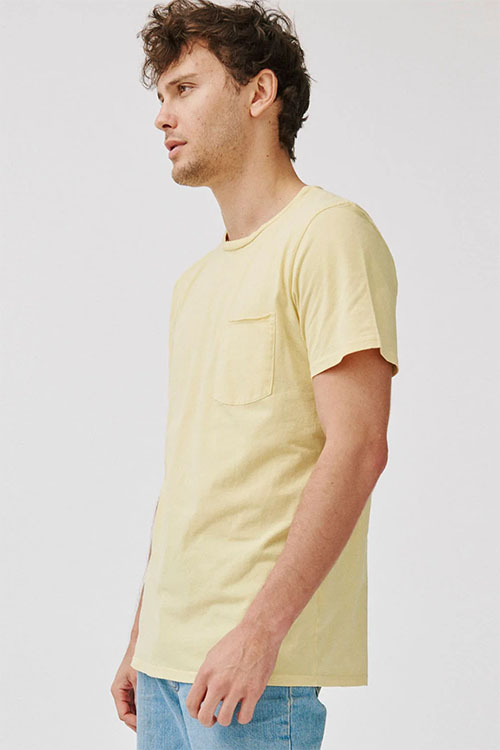 Young man wearing light yellow crew-neck t-shirt with front pocket.