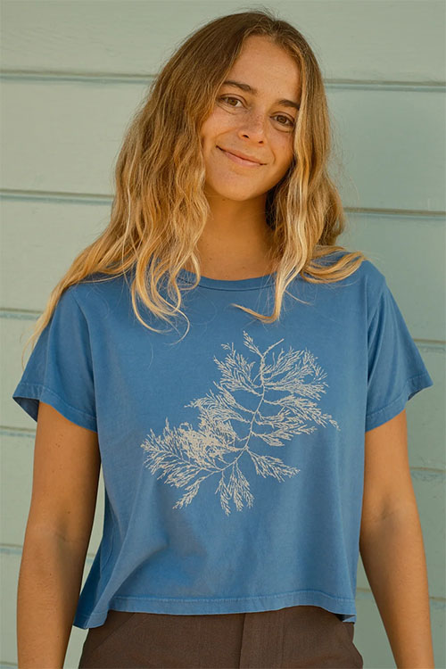 Young woman wearing light blue t-shirt with subtle plant print on chest.