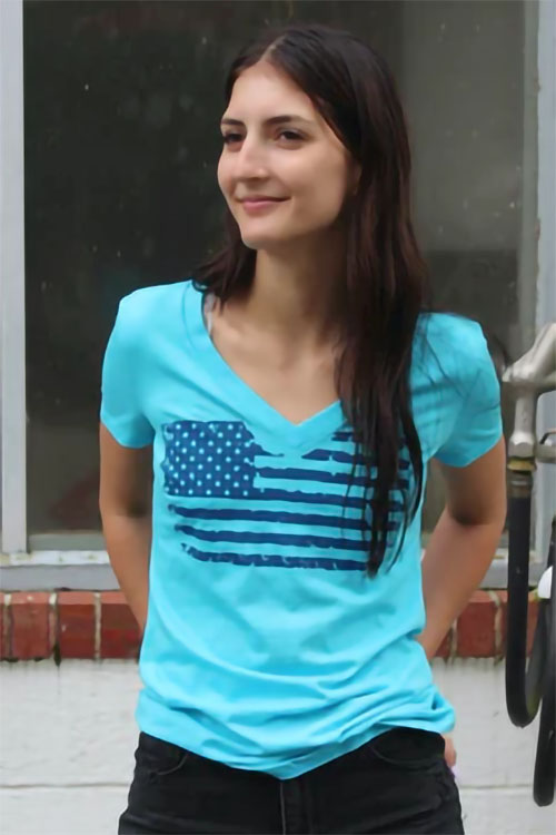 Young woman wearing blue v-neck tee with American flag print on chest.