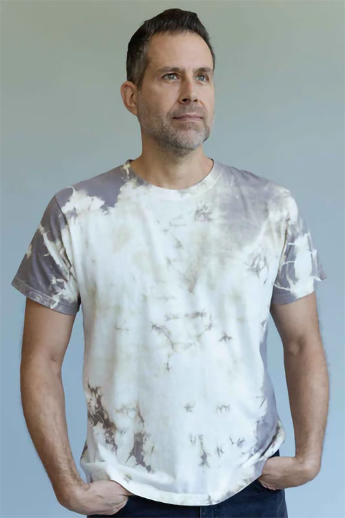 Man wearing short sleeve, crew-neck t-shirt in white with soft purple blotches.