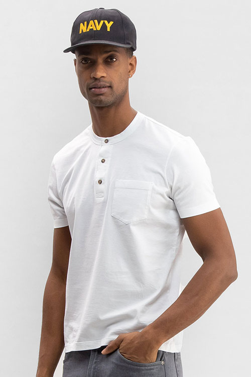 Man wearing white t-shirt with button-up collar and front pocket.