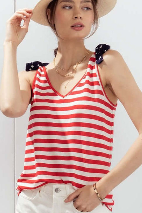 Woman wearing patriotic tank top with white and red horizontal strips, and blue star-spangled frills at the shoulders.