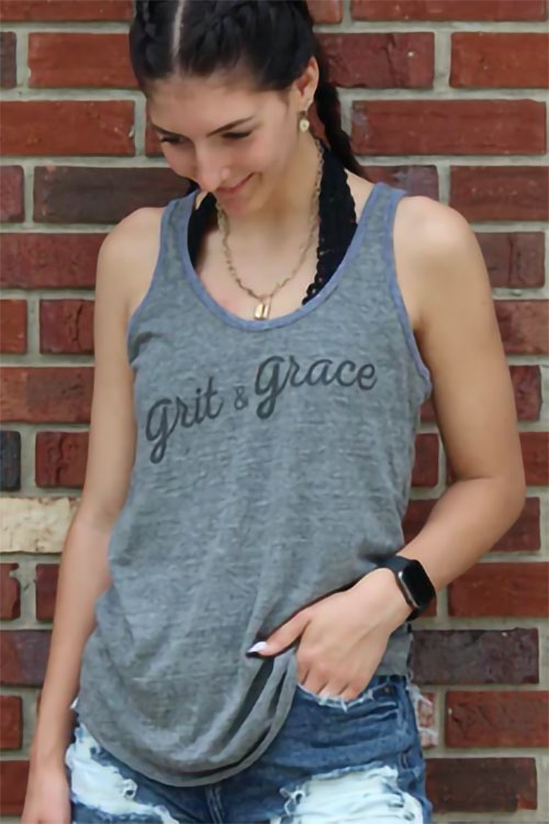 Woman wearing grey tank top with the words 'grit and grace' on the chest.