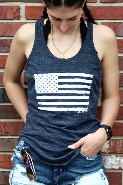 Woman wearing blue tank top with the American flag printed in white on the chest.